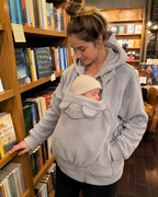 Mom browsing bookstore with baby sleeping in grey Snoozeroo fleece pouch